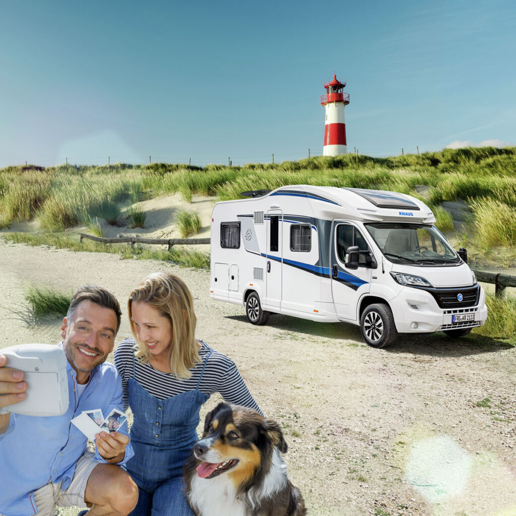 Eine Familie mit Hund genießt ihre Reise entlang der Küste in einem gemieteten Reisemobil, das an einer malerischen Küstenlandschaft geparkt ist. Sie erleben gemeinsam unvergessliche Momente in der Natur.